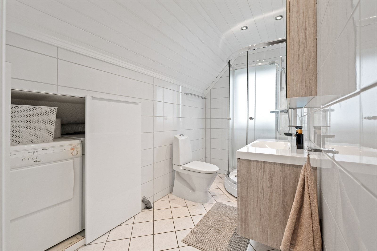 I vaskesonen er det avsatt plass til vaskemaskin og tørketrommel. Badet er for øvrig utstyrt med toalett, dusjkabinett og pen skuffeinnredning med heldekkende servant. Galleribilde
