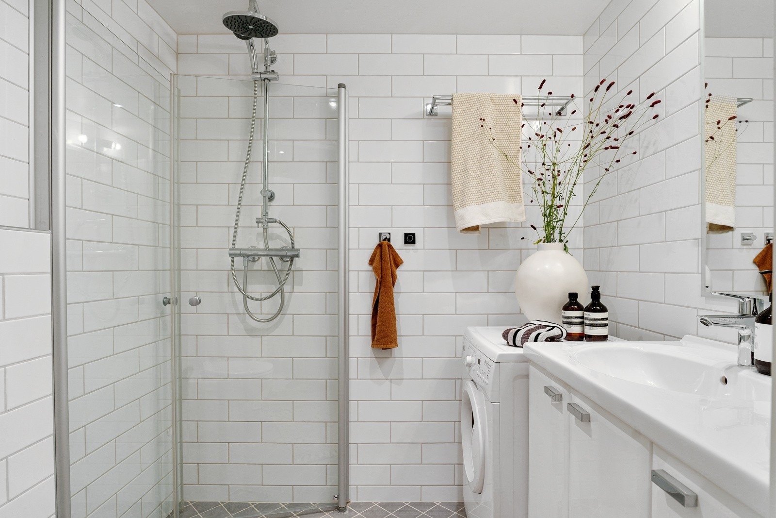 Delikat, flislagt bad med varmekabler, innredet med dusjnisje med svingbare glassdører og termostatstyrt dusjbatteri i krom med både hånd- og regnfallsdusj Galleribilde