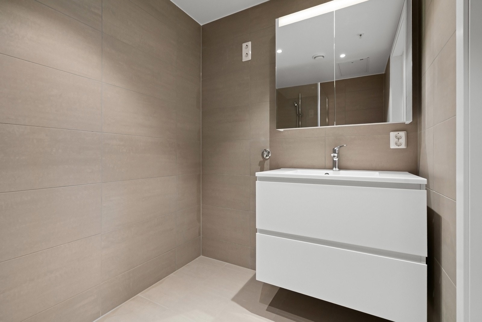 Smakfullt bad med moderne fliser. Badet leveres med i farge Marte Grey eller tilsvarende. Innredning med servantskap med skuffer fra Bano av type Home Eclipse, med grepsløse fronter. Bilde fra leilighet G305 Galleribilde