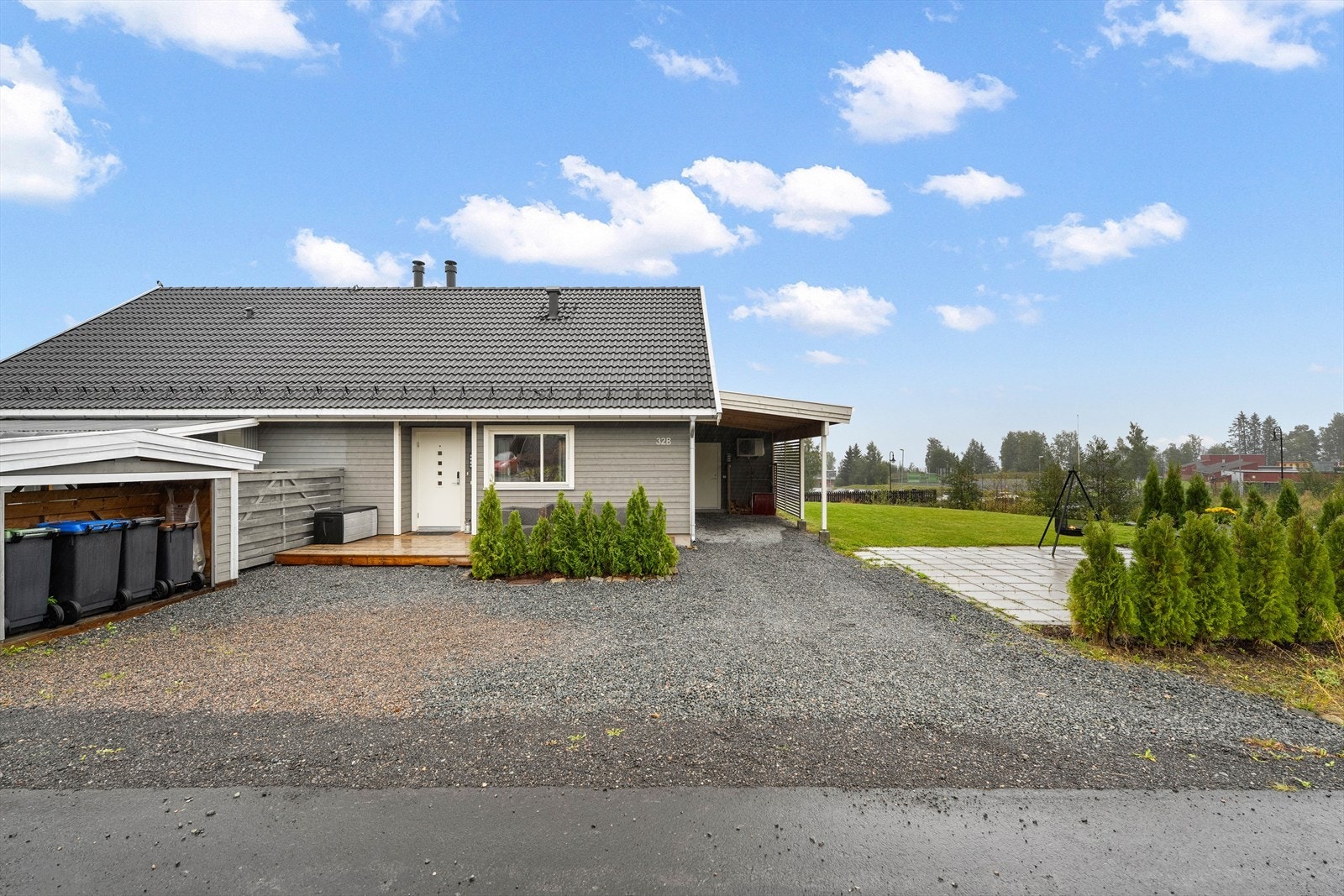 Gruset gårdsplass med parkeringsmuligheter samt carport m/lader for elbil, utebod, søppelhus og terrasseplatting. Galleribilde