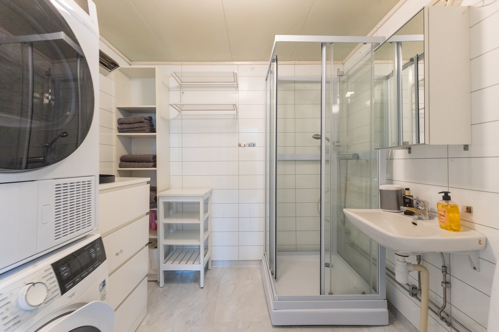 Stort bad med plass til både vaskemaskin, tørketrommel, skjenk og hylleseksjon. Galleribilde