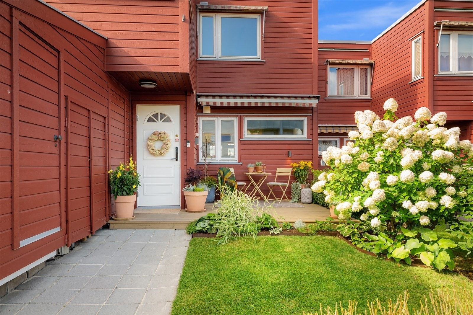 Ved inngangen til huset er det enkel tilgang til en praktisk utebod/ sportsbod. Den frodige hortensiaen er virkelig et vakkert syn på sommerstid. Galleribilde