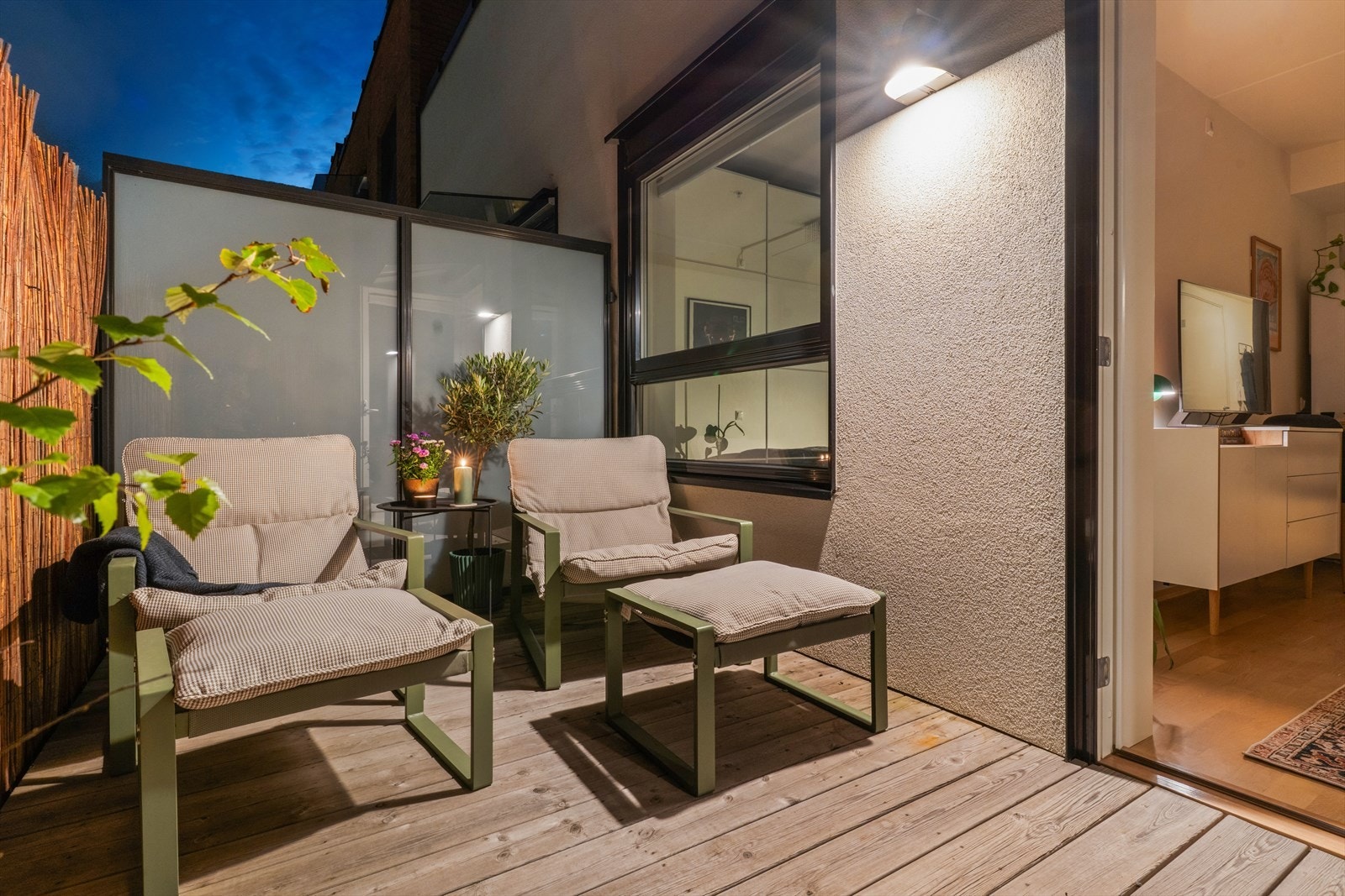 Balkongen har terrassebord i trevirke, aluminiumrekkverk med stående spiler og praktisk belysning med stikkontakt. Galleribilde