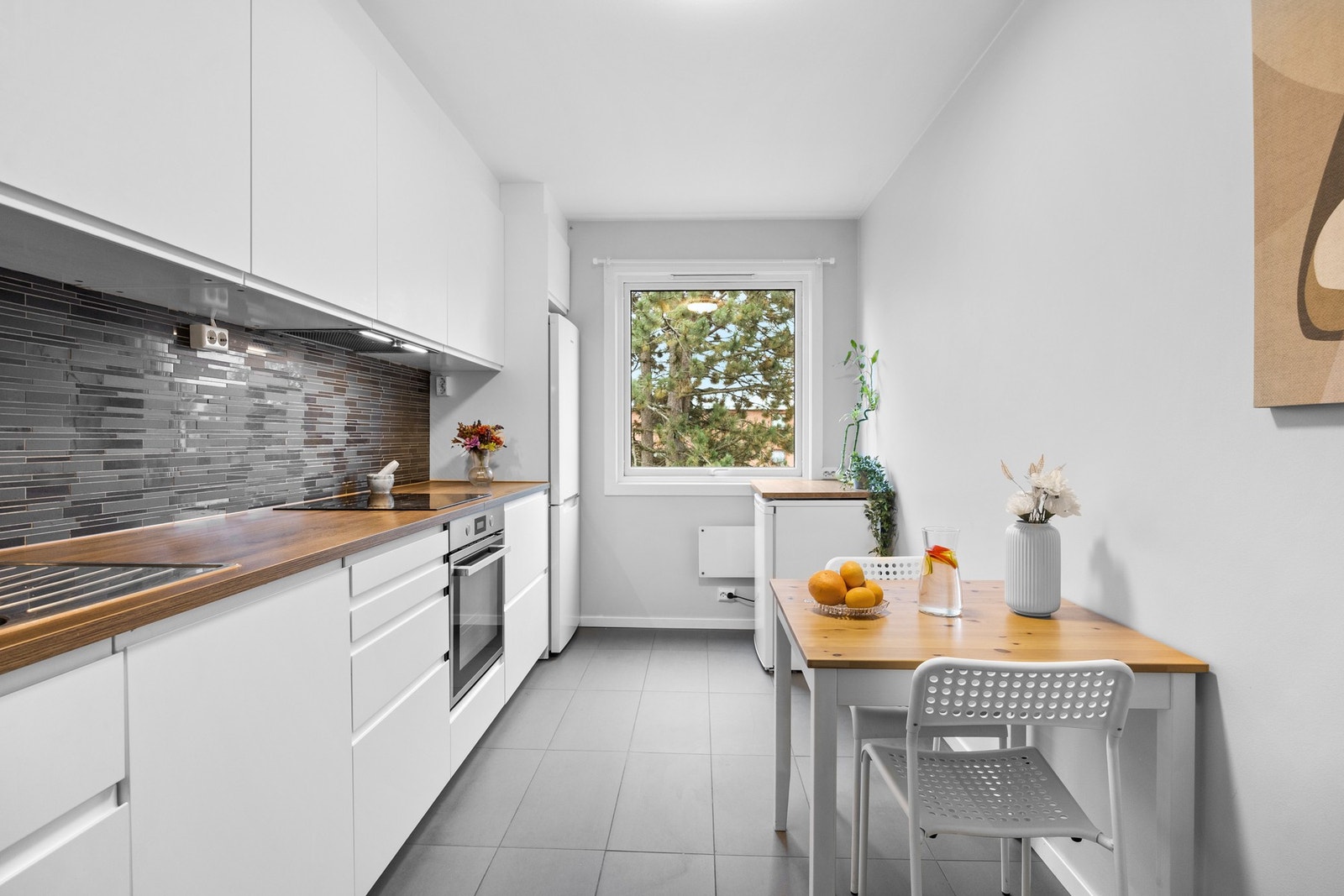 Adskilt IKEA kjøkken med god størrelse, tilpasset både matlaging og en hyggelig spiseplass for to. Galleribilde