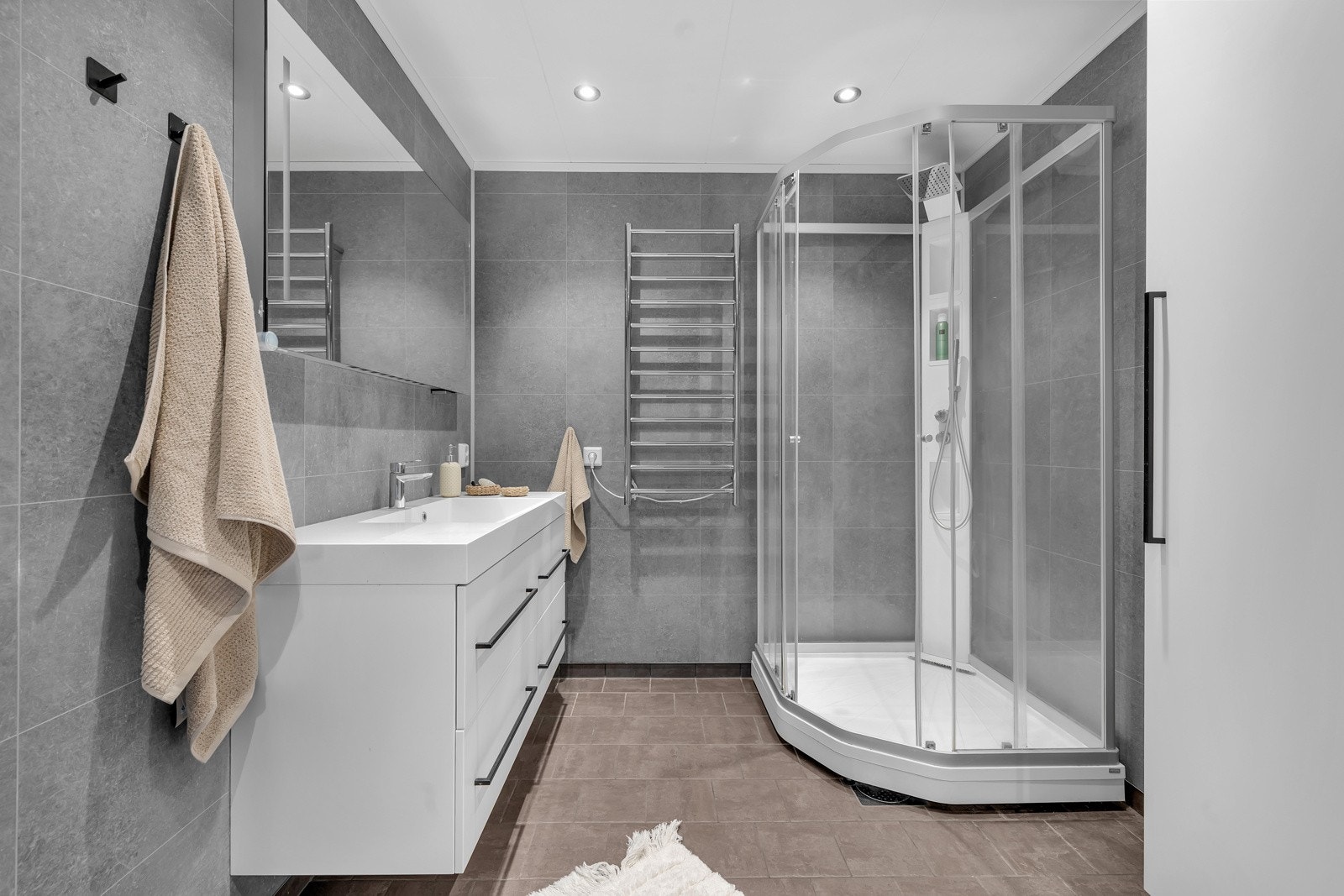 Praktisk og pent bad med dusjkabinett, innholdsrik innredening med heldekkende servant, håndkletørker m.m. Galleribilde