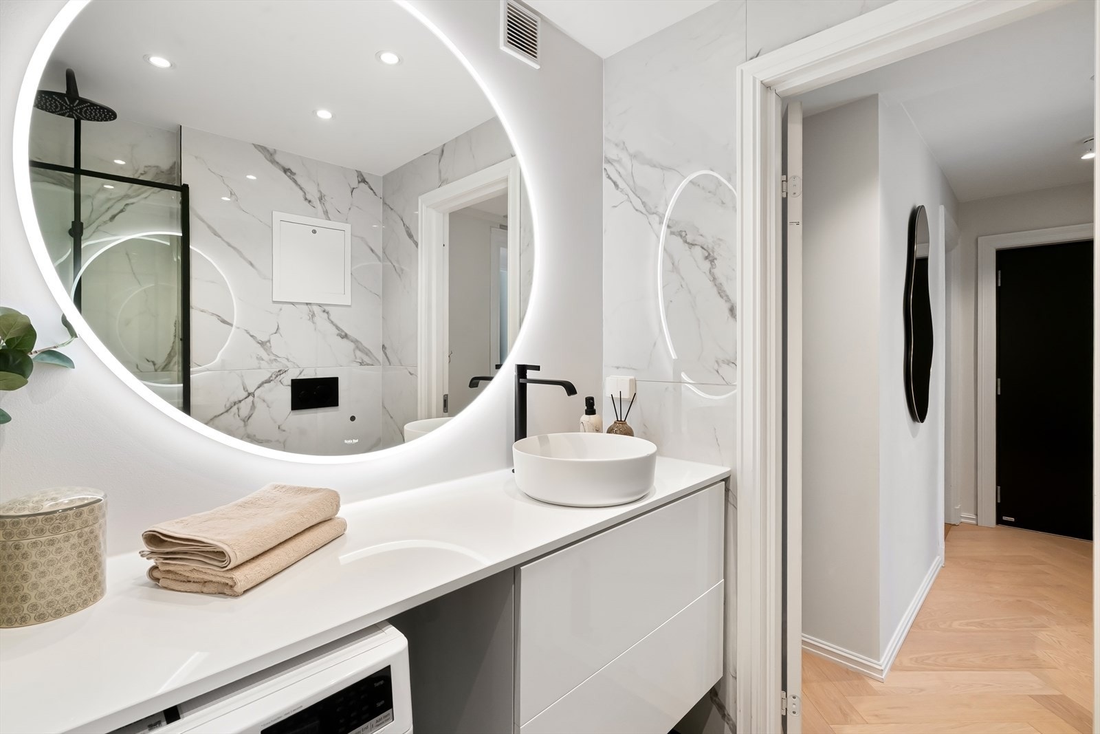 Badet er innredet med benkeskap med glatte fronter og speil med belysning. Galleribilde