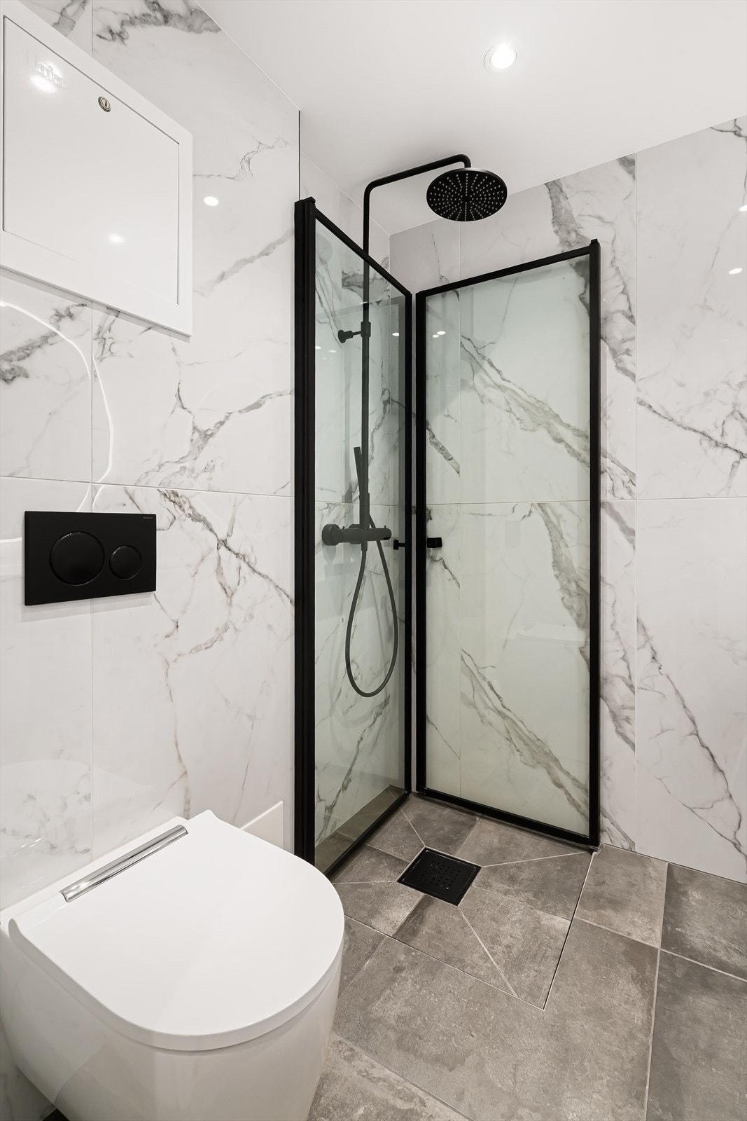 Badet er utstyrt med dusj med innfellbare dører i herdet glass, servant, vegghengt toalett og opplegg for vaskemaskin. Galleribilde