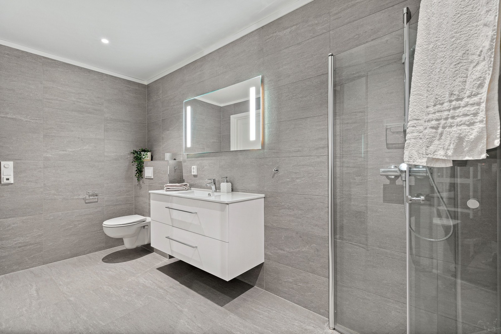 Dusjhjørne med glassdører og vegghengt toalett. Galleribilde