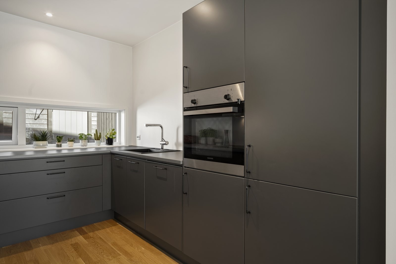 De mørke, matte frontene gir et eksklusivt uttrykk, mens de rene linjene og integrerte håndtakene bidrar til et minimalistisk preg. Galleribilde