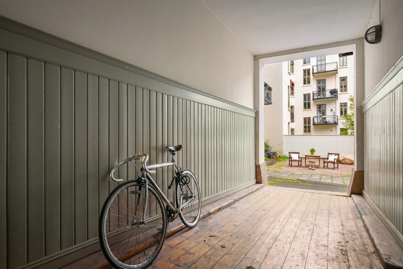 Bakgården har singlet areal, hellelagt gangsti og skjermende levegger på sidene. Galleribilde