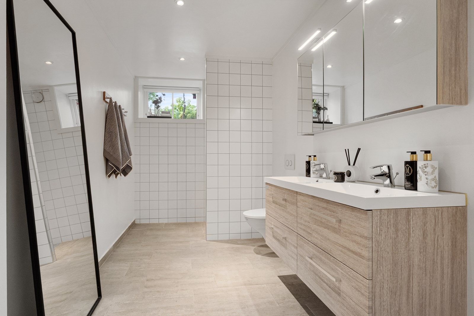 Bad nr 3 - flislagte overflater med dobbelt servant og oppbevaring. Vegghengt toalett, dusj-hjørnet, samt downlights i himling og varmekabler i gulv. Galleribilde