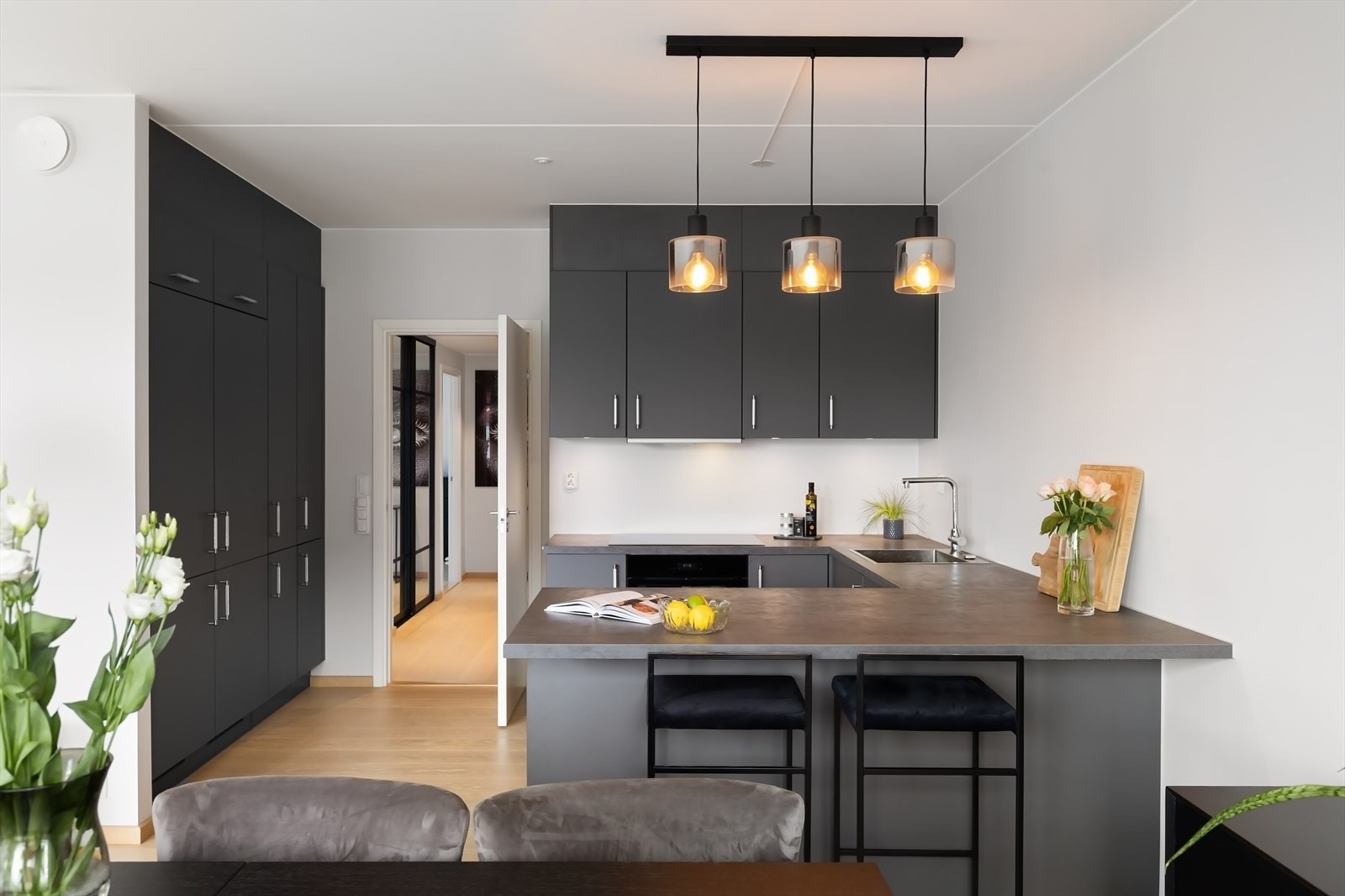 Pent og spesialtilpasset kjøkken med slette fronter, belysning under overskap og laminat benkeplate. Galleribilde