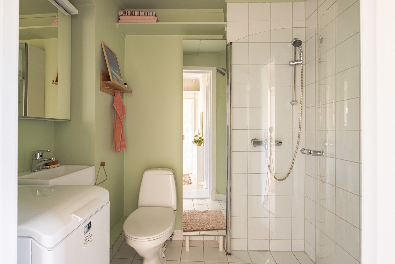 Leiligheten har et lyst og pent baderom. Baderommet har hvite fliser på gulv (med gulvvarme) og på veggene i dusjsonen, mens de øvrige veggene er malt i fin grønnfarge. Galleribilde