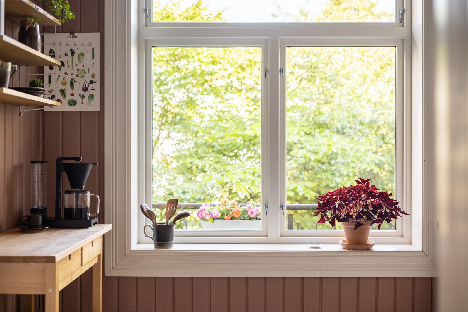 Et stort vindu slipper rikelig med naturlig lys inn og gir flott utsyn mot grønne omgivelser og en blomstrende balkongkasse. Galleribilde