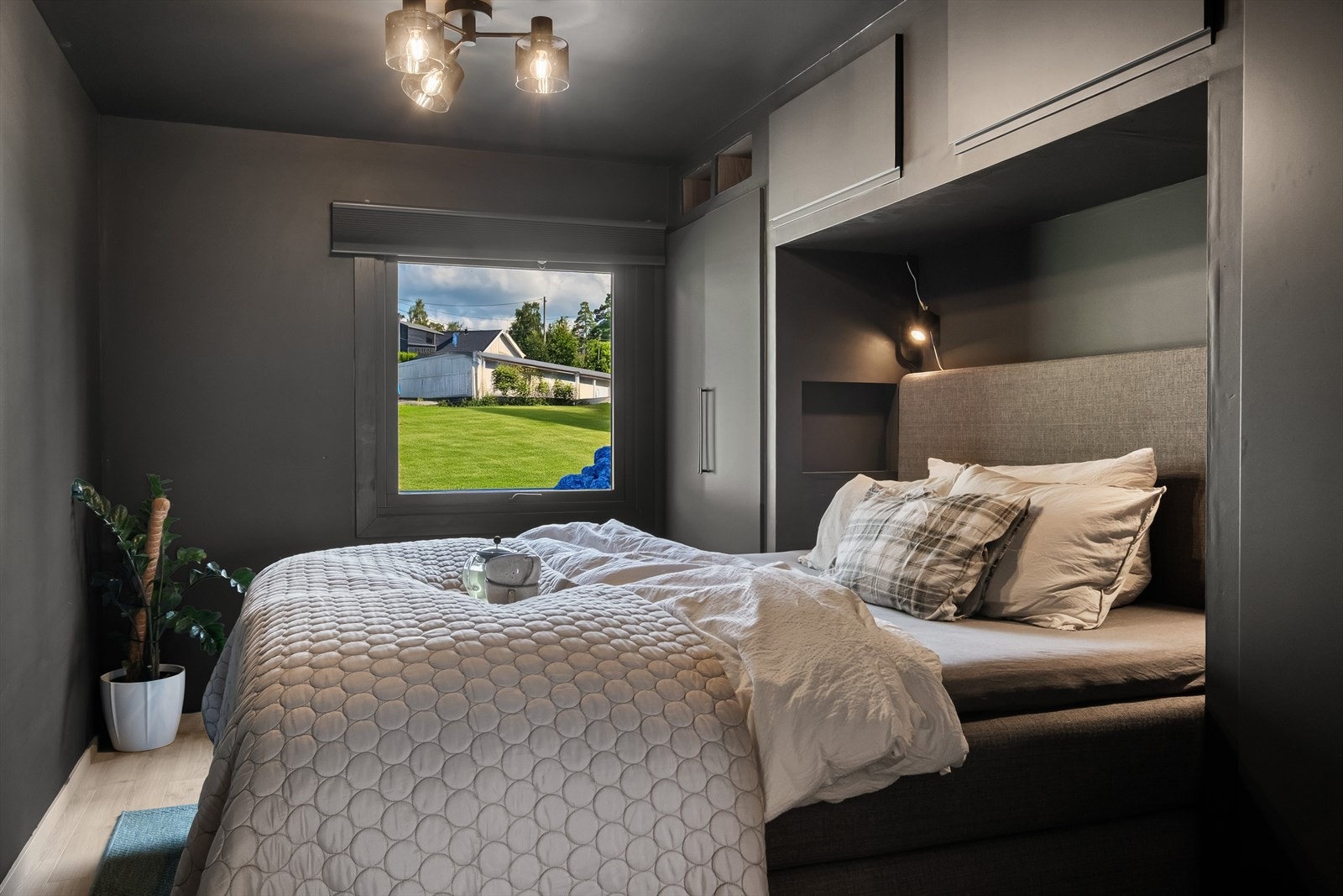 Innbydende hovedsoverom med lune farger og smarte oppbevaringsløsninger. Vinduet slipper inn rikelig med dagslys og gir en fredelig utsikt mot grønne uteområder Galleribilde