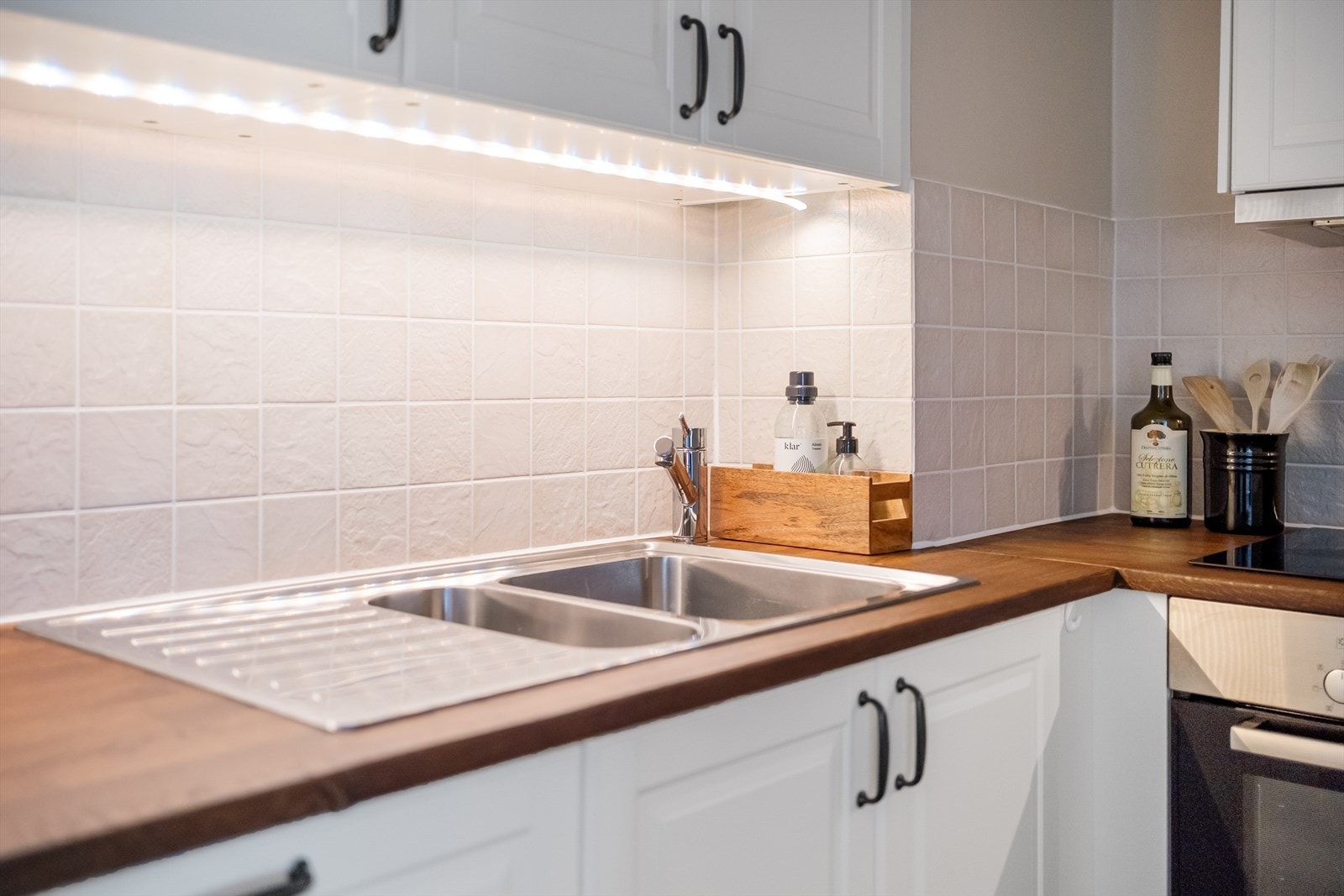 Flislagte vegger med nedfelt vask og benkeplate av heltre. Galleribilde