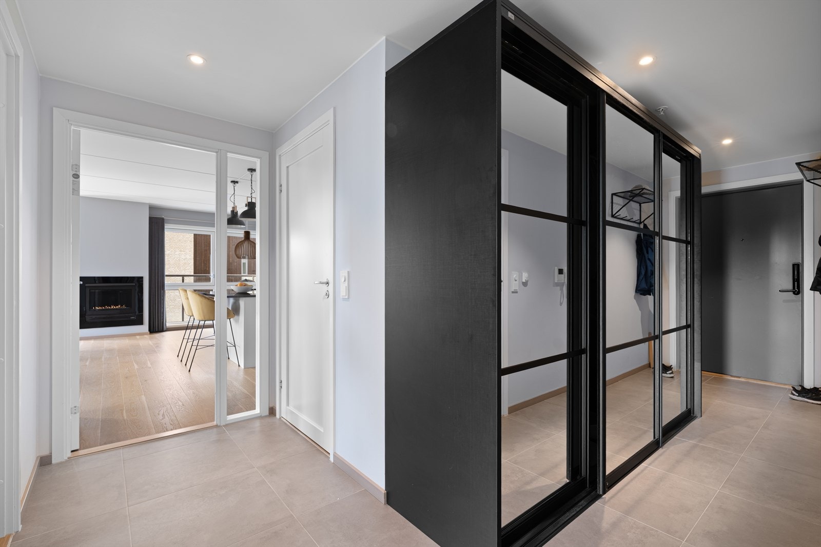 Flislagt gang med skyvedørsgarderobe og spotter i himling. Galleribilde