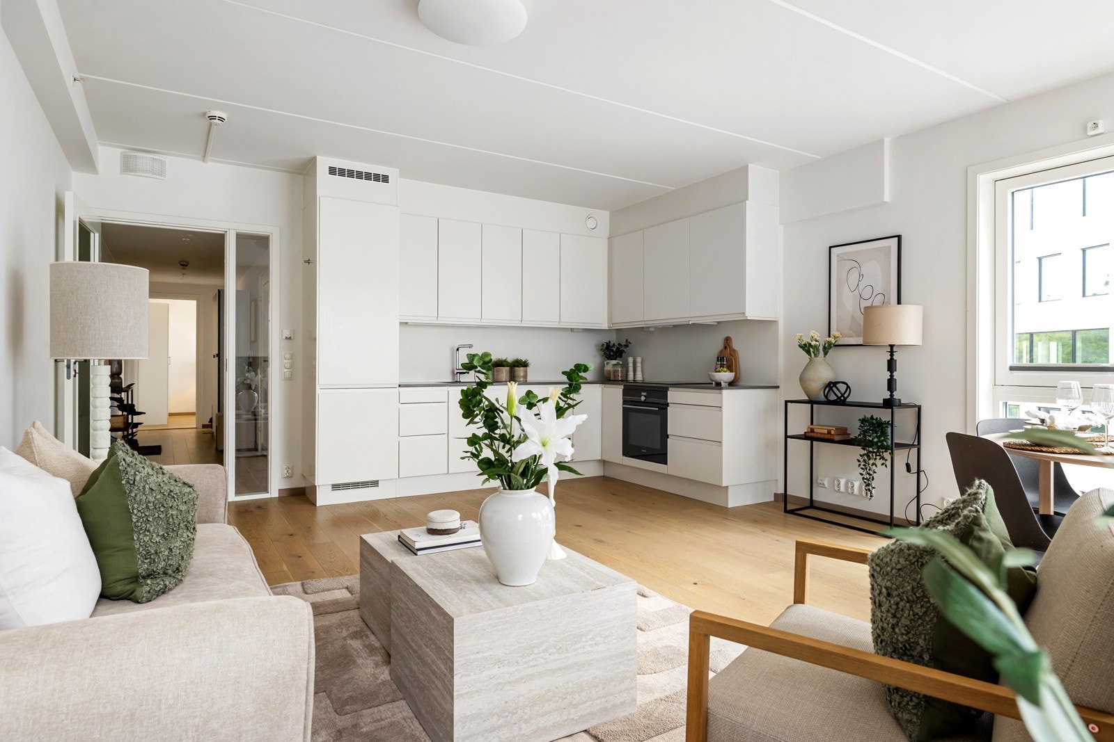 Leiligheten har en tidløs kjøkkeninnredning fra Sigdal med glatte hvite fronter og benkeplate i komposittstein Galleribilde