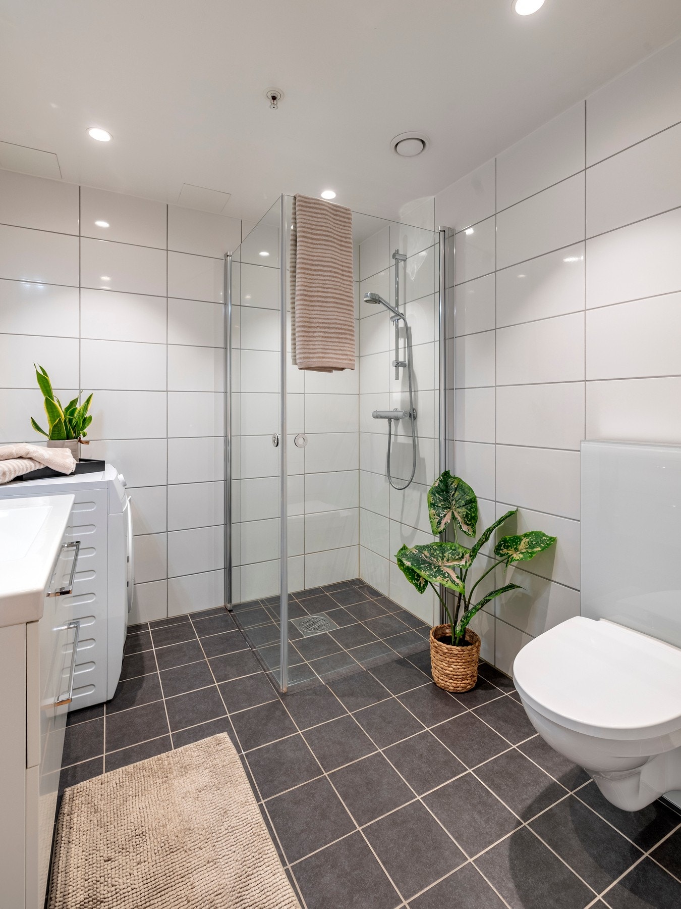 Innredningen består av servantinnredning, speil med lys på vegg over servant, vegghengt toalett og dusjhjørne med svingbare glassdører. Galleribilde