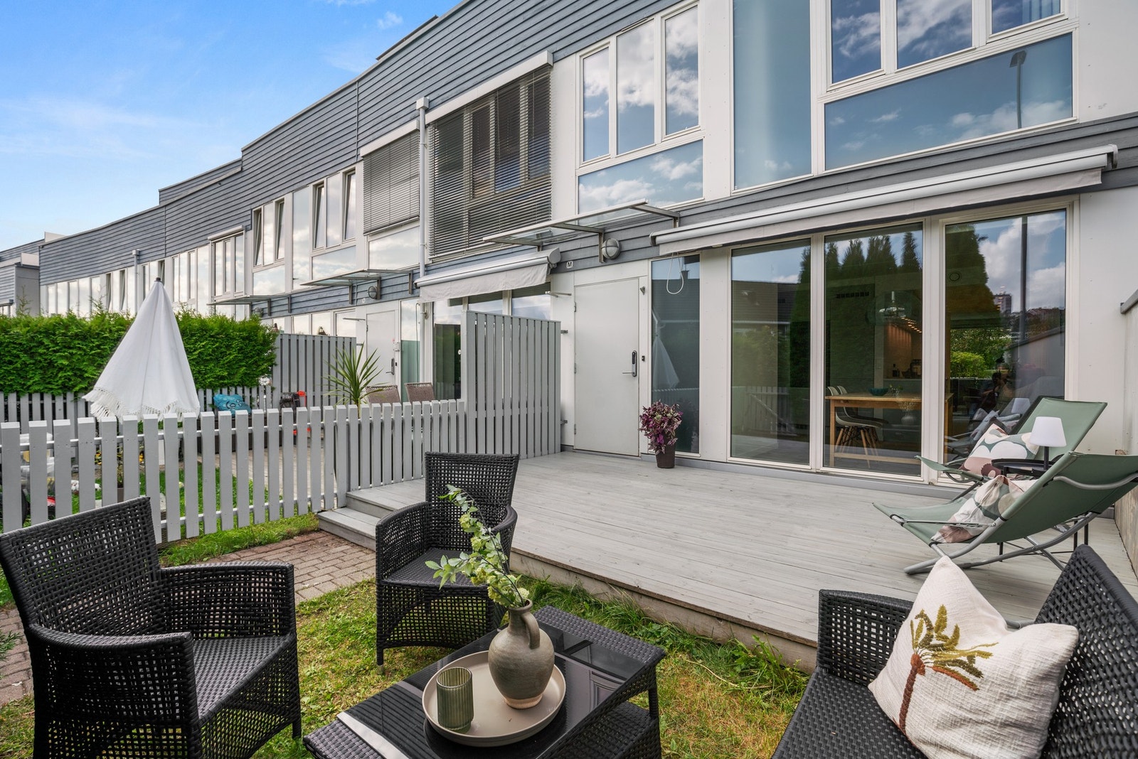 Den sydvendte uteplassen ved inngangspartiet har både terrasse og plen. Det er gjerde og hekk på tre sider, som sørger for at plassen blir usjenert og privat Galleribilde