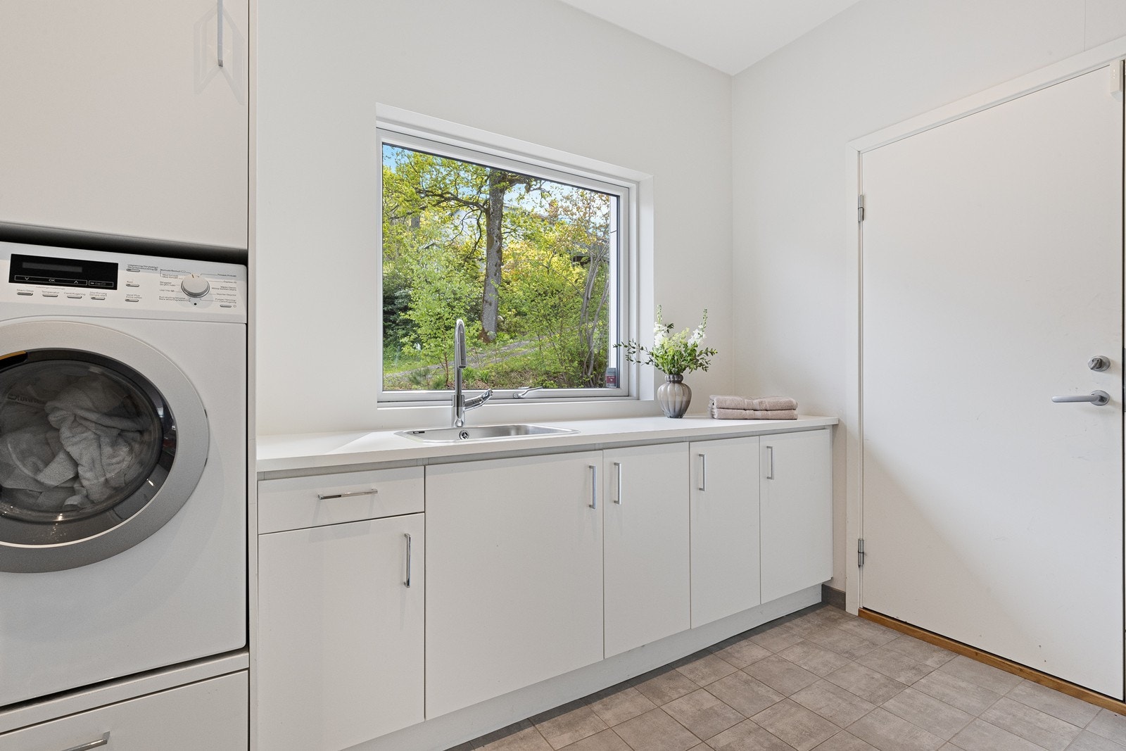 Godt innredet vaskerom innenfor hallen og med dør videre til garasjen og bod med smørebenk. Galleribilde