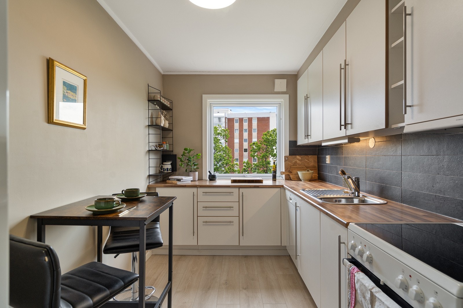 Kjøkkenet ligger i egen sone, med glatte fronter, laminat benkeplate og integrerte hvitevarer som kjøl/fryseskap, komfyr og oppvaskmaskin. Her er det god skapplass og en funksjonell arbeidsflate. Galleribilde