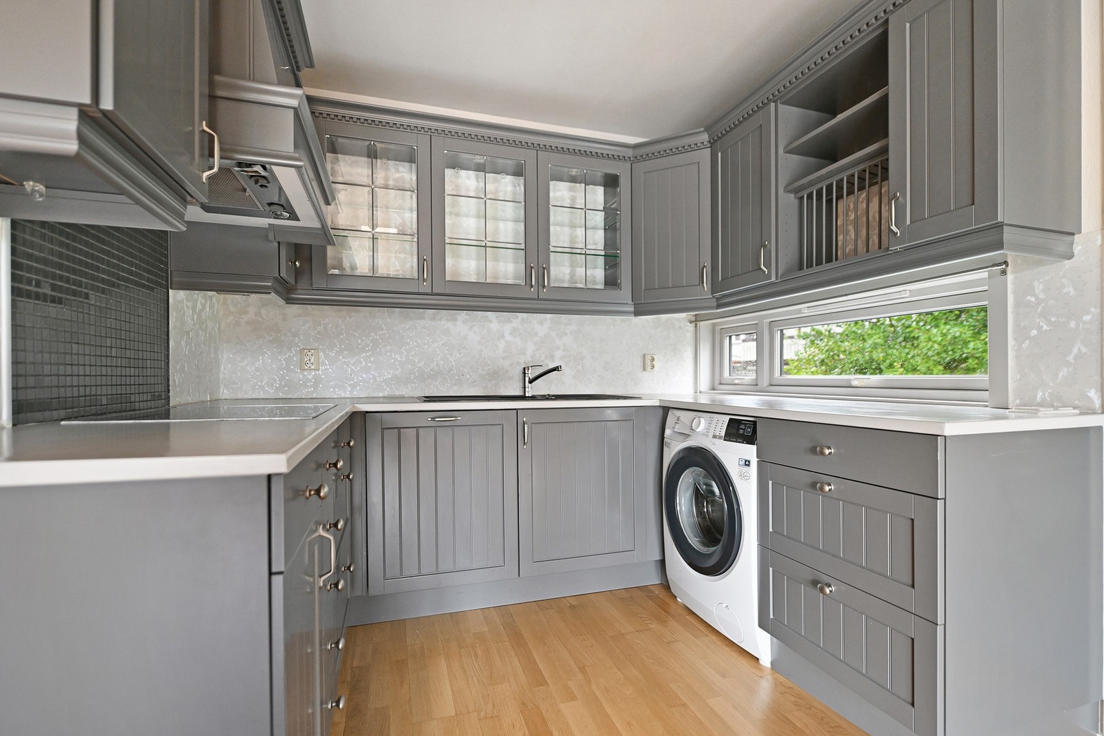 Kjøkkeninnredning fra Huseby med malt heltre benkeplate og integrerte hvitevarer fra MIELE som komfyr, kombidampovn, platetopp, oppvaskmaskin og kjøl/frys. Det er samtidig opplegg for vaskemaskin på kjøkkenet. Galleribilde