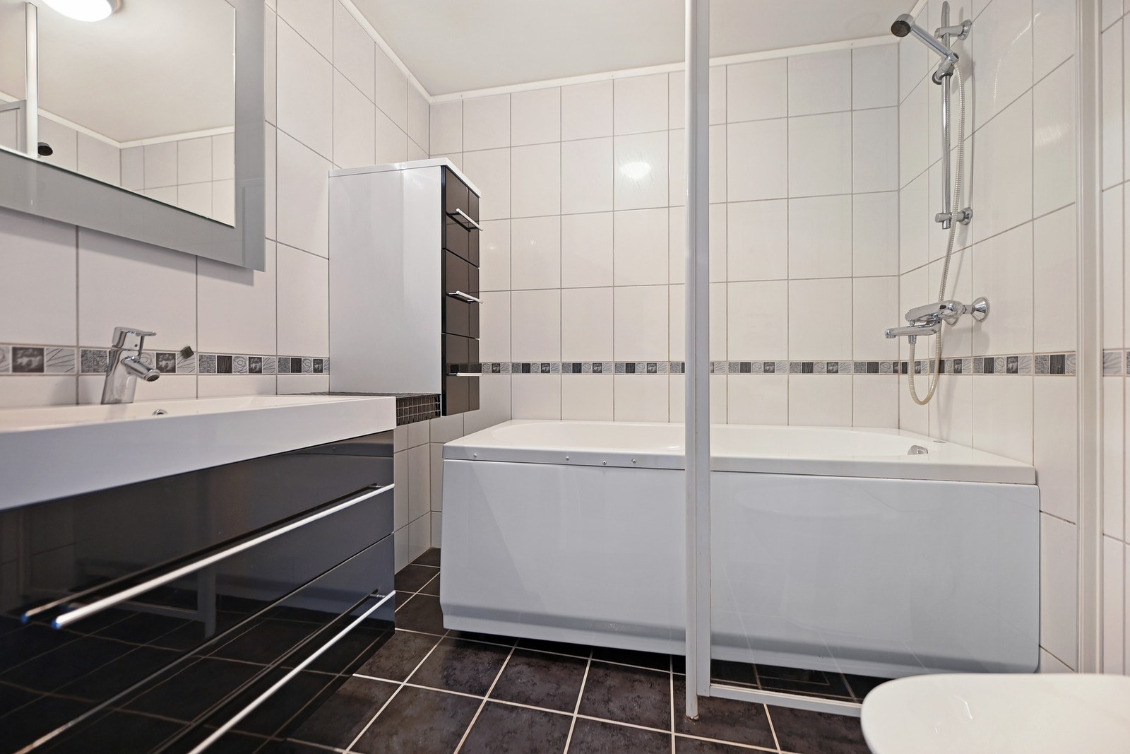 Leiligheten har et delikat bad. Innredningen er holdt i lyse og nøytrale tidsriktige farger, gulvet er belagt med mørke fliser og har varmekabler som gir behagelig, barfotvennlig varme. Galleribilde