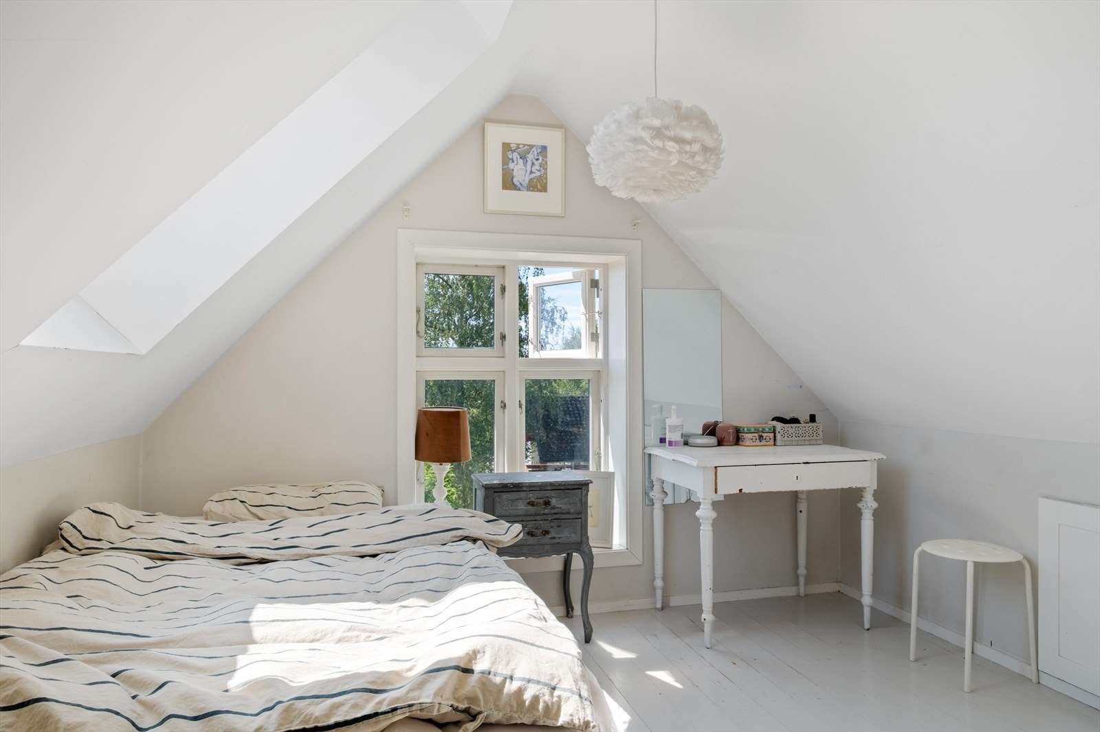 Loftstuen er et hyggelig rom med skråtak. Store vinduer slipper inn naturlig lys, som gjør rommet lyst og behagelig. Galleribilde