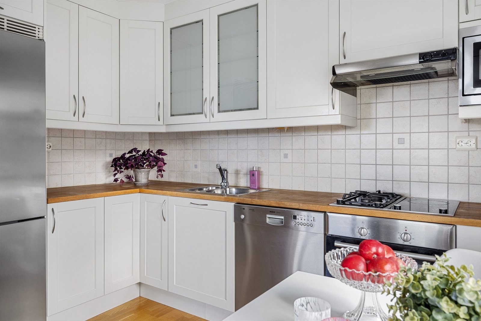 Både fint og praktisk med fliser i benkeryggen og belysning under de takhøye overskapene. Galleribilde