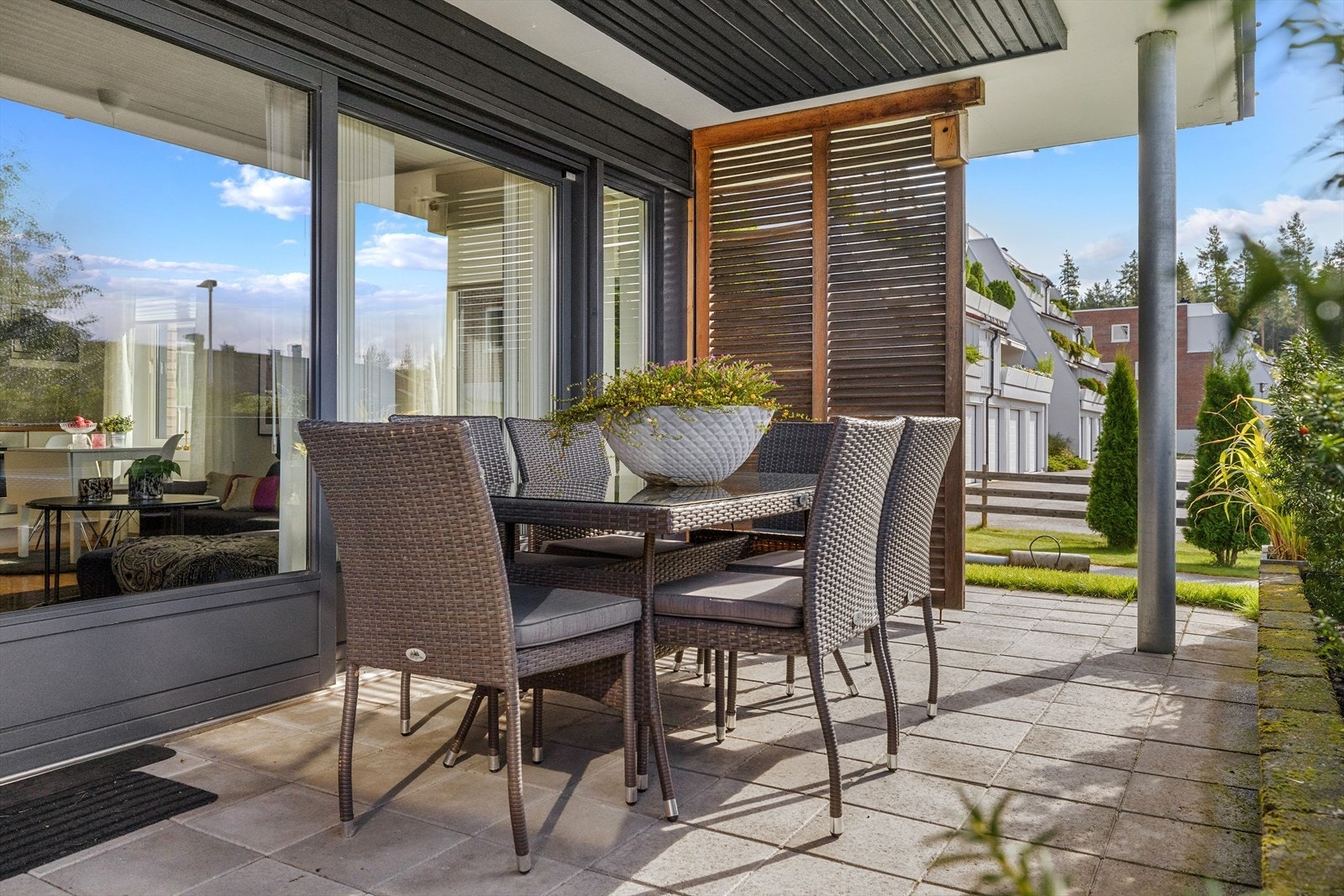 Uteplassen er overbygget, har betongheller på gulv, blomsterkasser av belegningsstein og levegg i treverk. Galleribilde