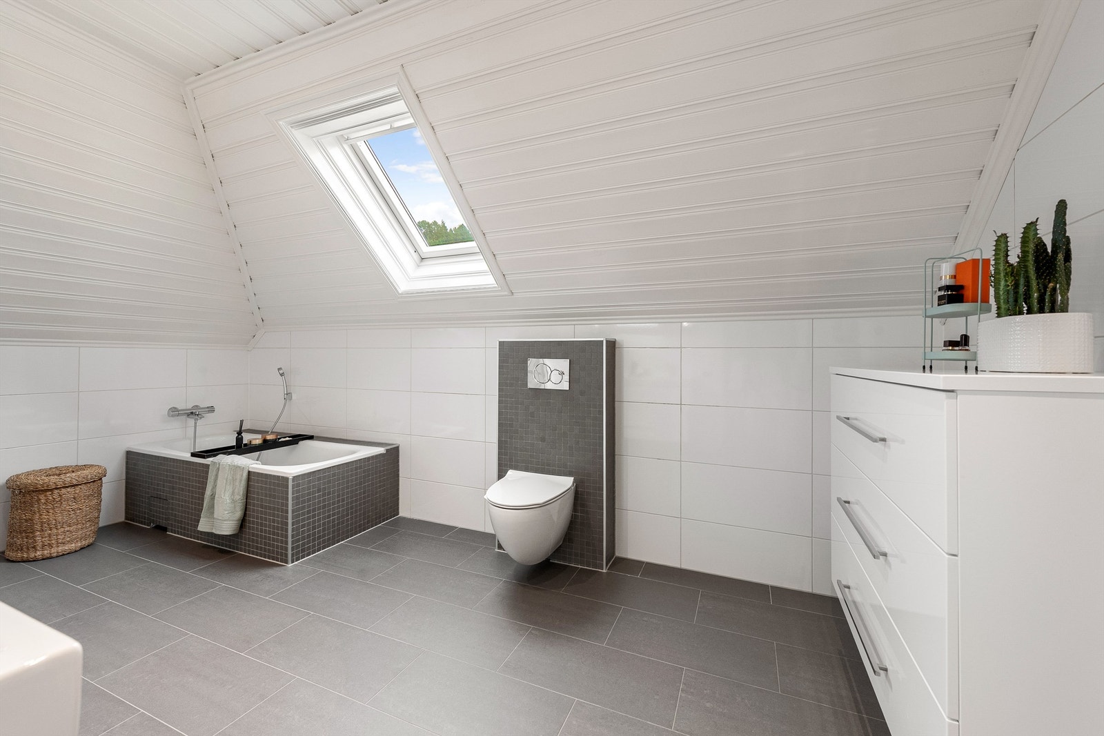 Badet på loft har innebygget badekar og vegghengt toalett. Gode lysforhold fra takvindu. Galleribilde