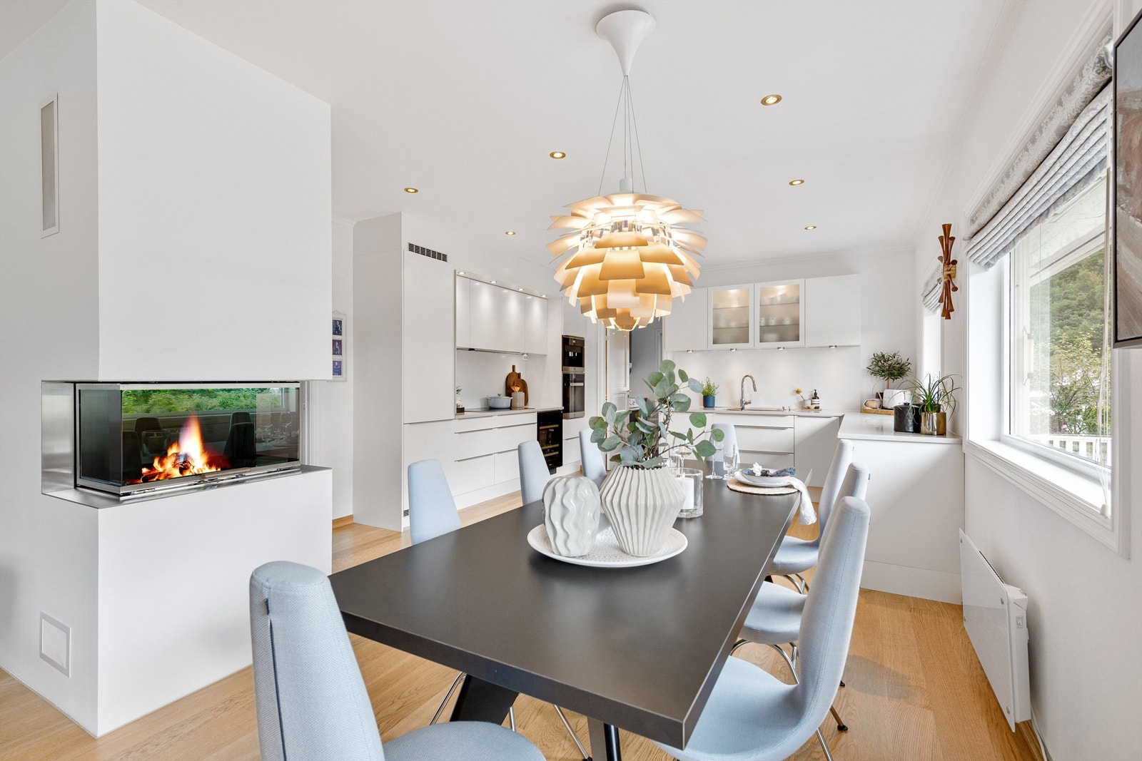 Det er god plass til romslig spisestue i tlknytning til kjøkkenet. Flott og moderne peis med glassdør som kan sees fra både kjøkken og stue Galleribilde