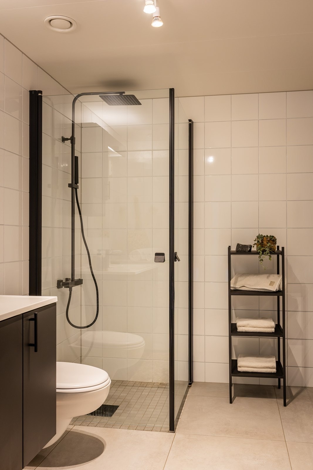 Badet består av vegghengt toalett, servantskap og dusjhjørne med glassdører. Galleribilde