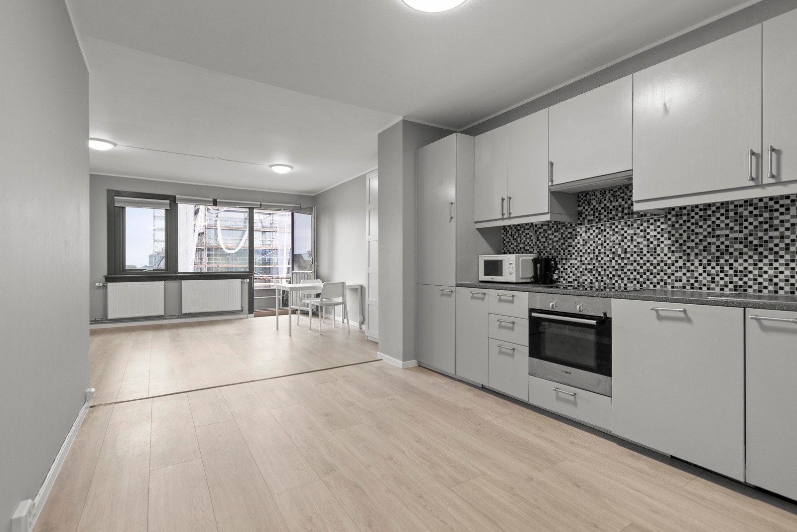 Lys kjøkkeninnredning med glatte fronter og laminat benkeplate. Her har man god plass til spisebord. Galleribilde