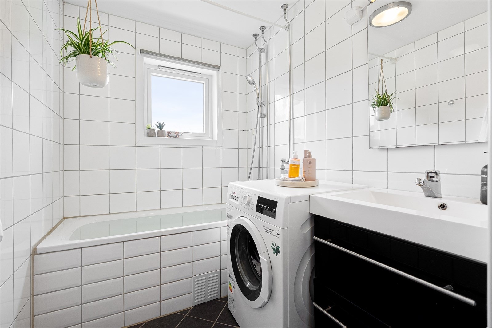 Badet er innredet med WC, et deilig innmurt badekar, servant med ettgreps blandebatteri i innredning og opplegg for vaskemaskin. Galleribilde