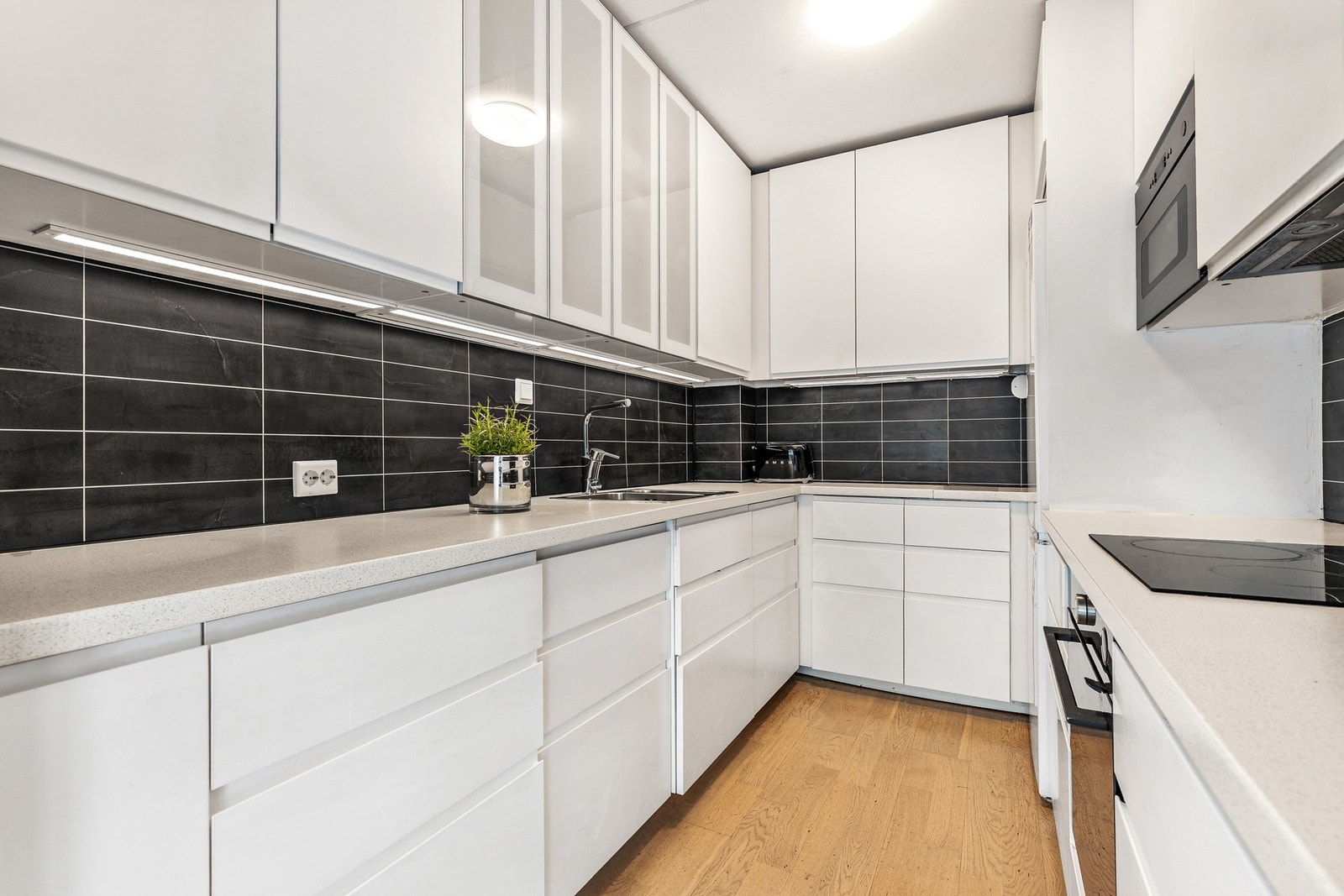 Store skap og skuffer gjør det enkelt å holde kjøkkenet ryddig og organisert, slik at man alltid har det man trenger lett tilgjengelig. Innredningen består av glatte fronter og laminat benkeplate med vask. Galleribilde