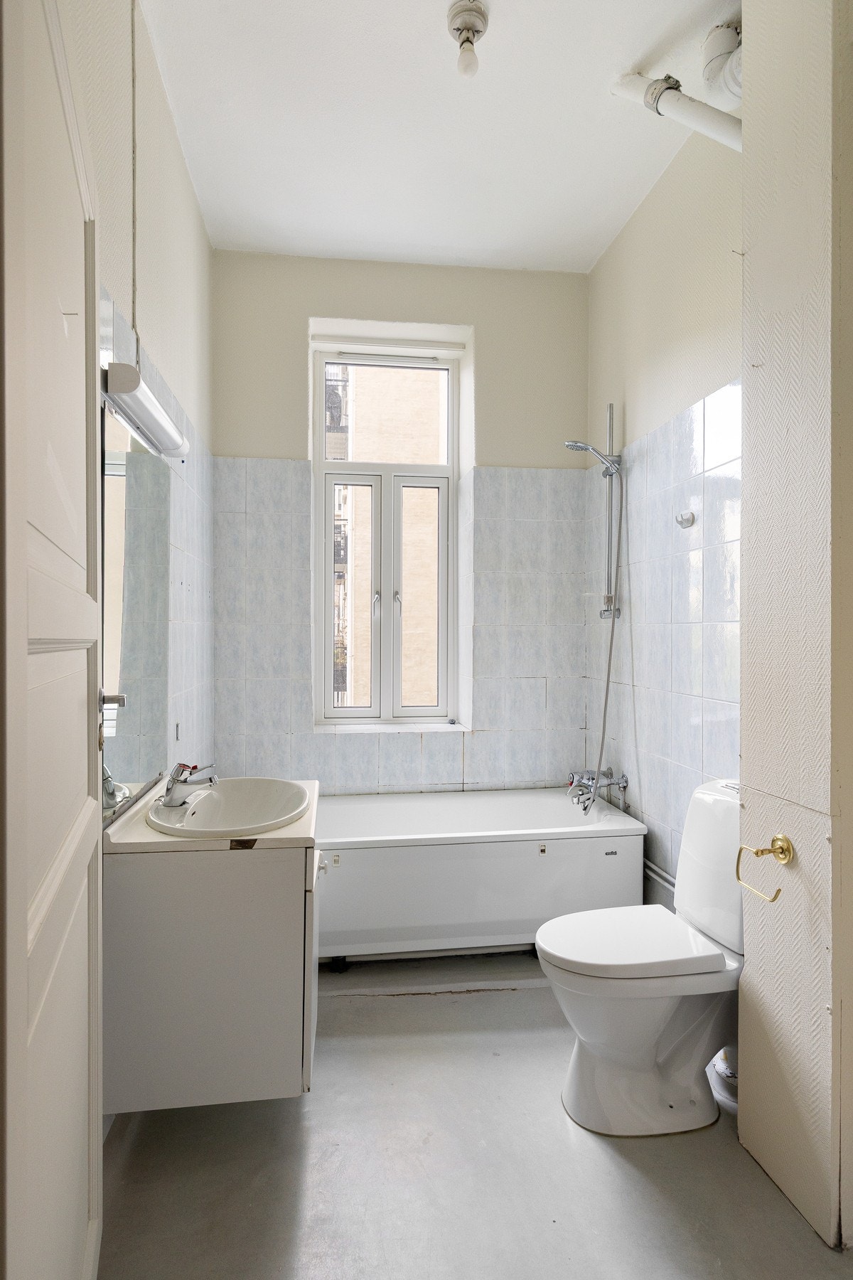 Romslig baderom med lyse overflater og vindu. Galleribilde