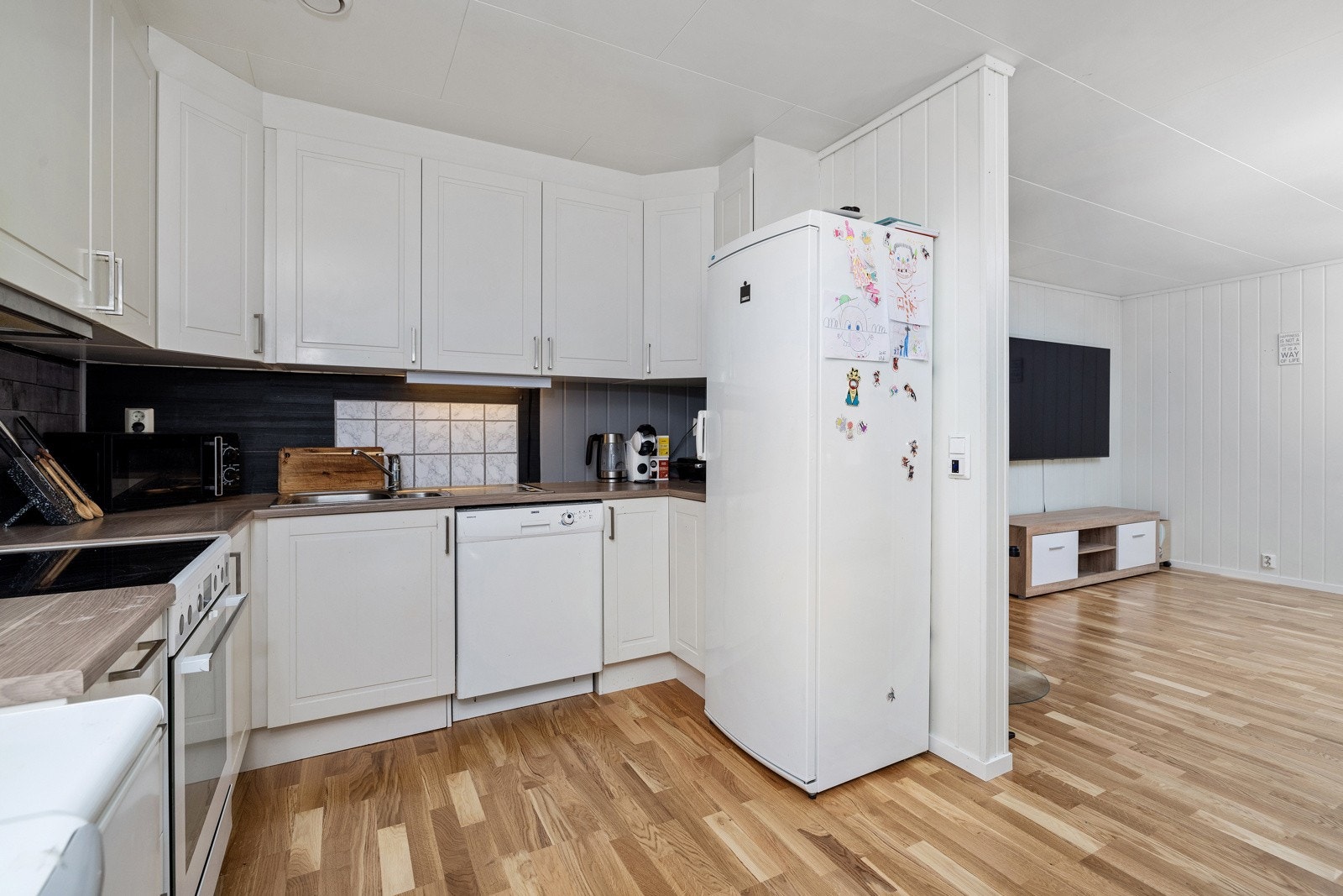 Stilrent kjøkken med åpen løsning mot stue. Galleribilde