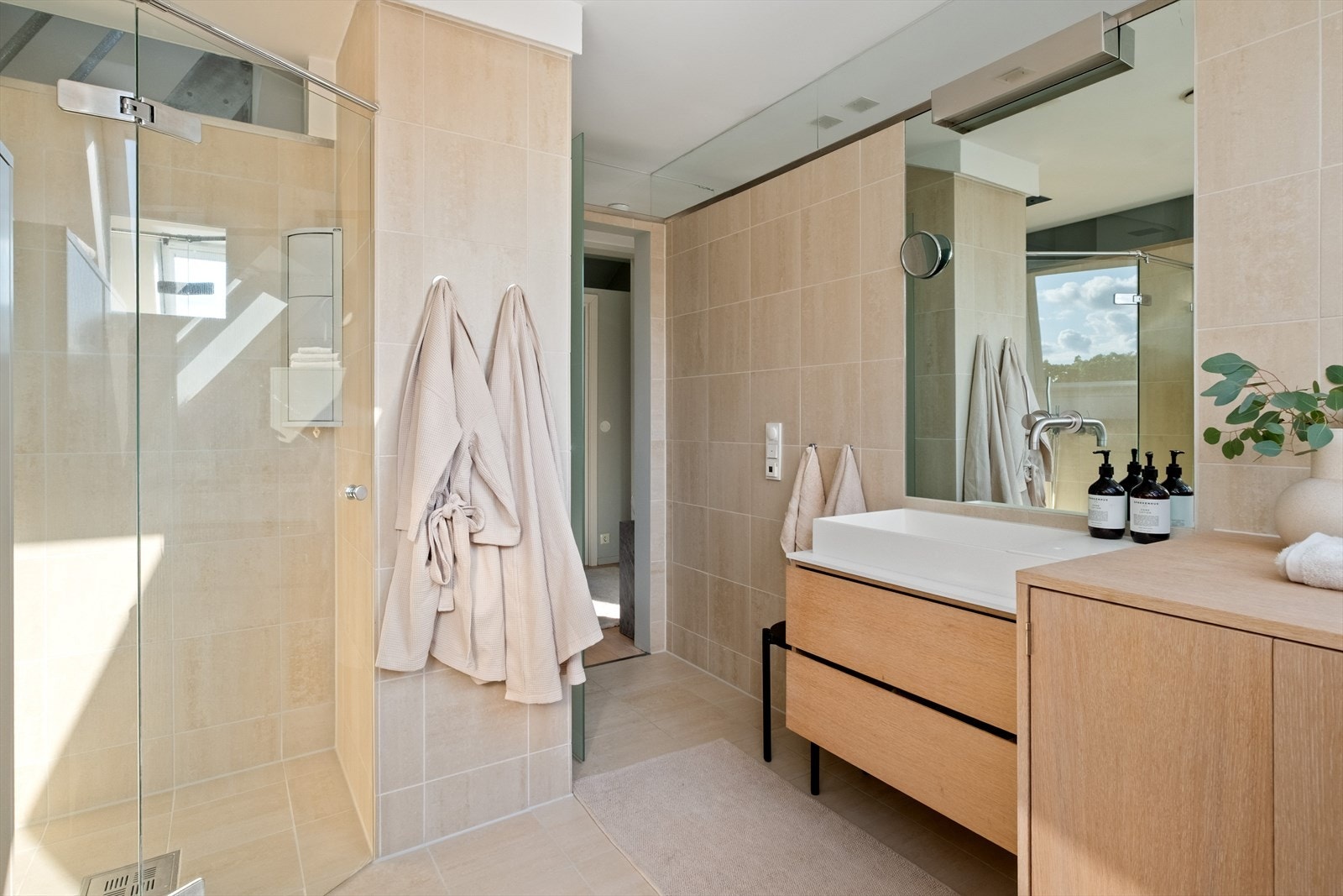 Badet er innredet med vegghengt toalett, møbelsnekret innredning med servant og armatur fra Vola, dusjhjørne med svingbar glassdør. Galleribilde