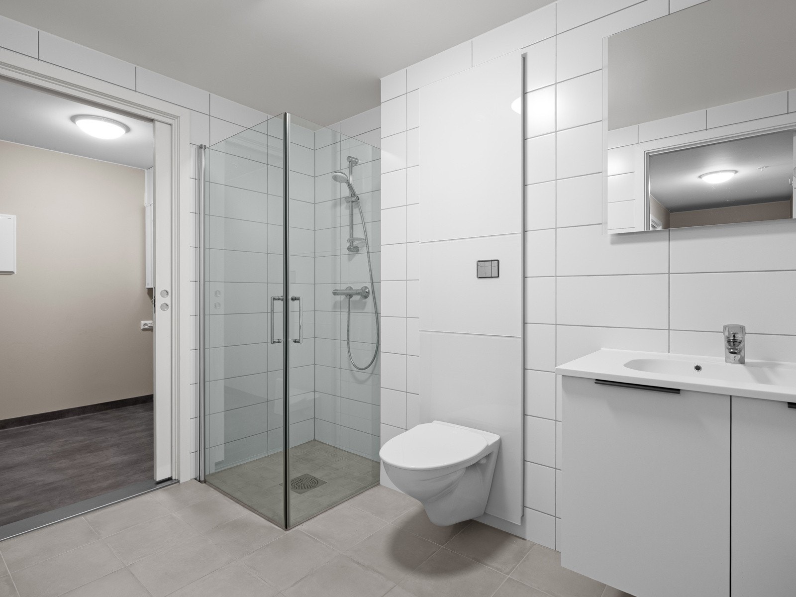 Badet har dusjhjørne med innfellbare glassdører, servant med underskap og speil. Galleribilde