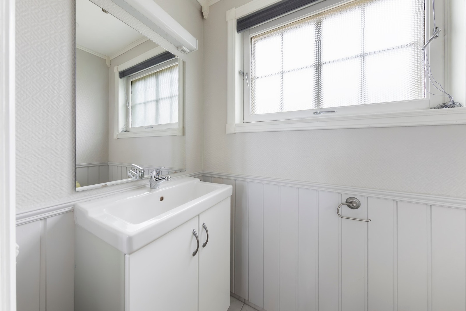 Toalettrom har flislagt gulv, vegghengt toalett og foliert servantskap med heldekkende servant Galleribilde