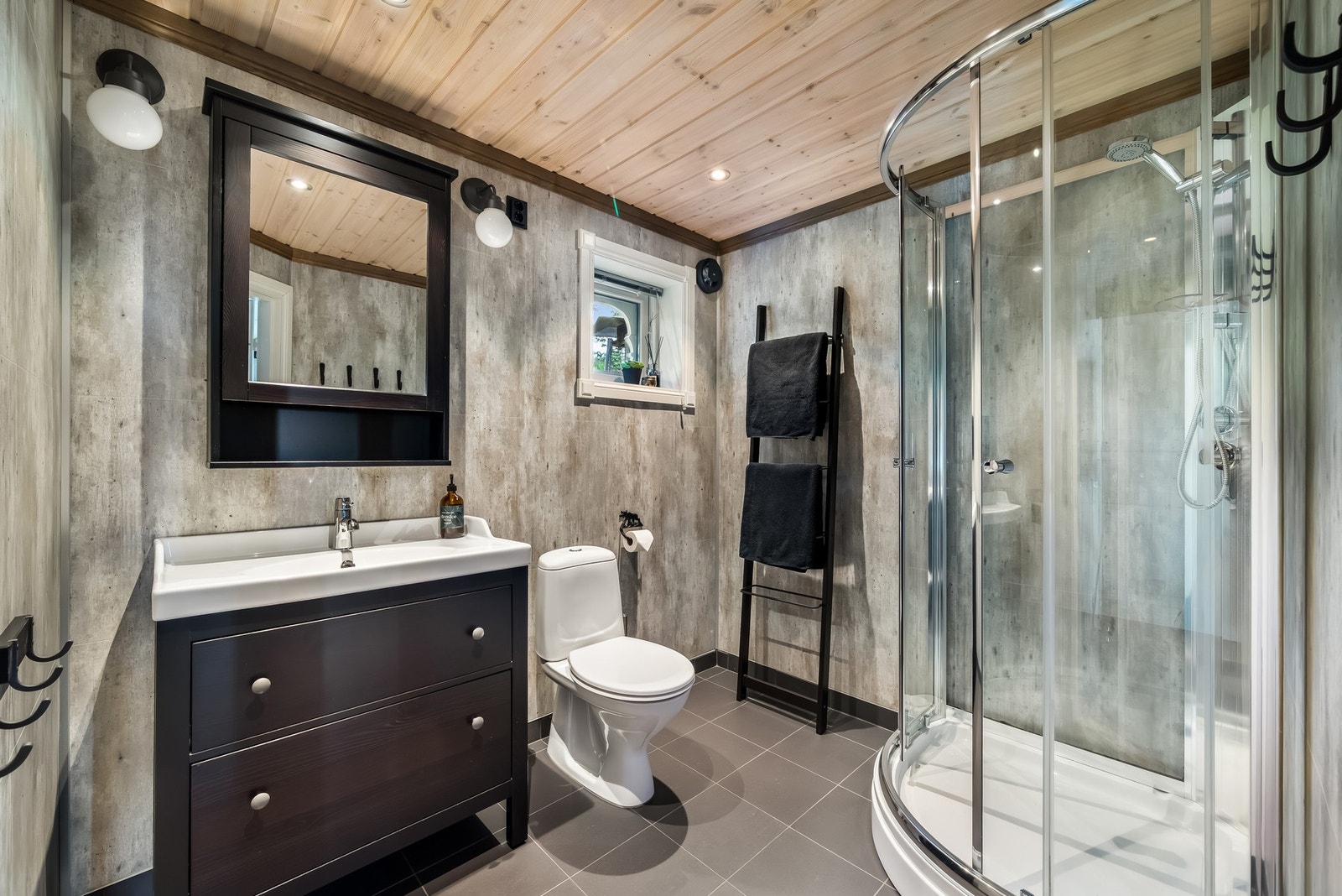 Pent baderom fra byggeår 2016. Gulvflater med fliser og gulvvarme, veggflater med baderomsplater, gulvmontert toalett, dusjkabinett, innredning med slette fronter og heldekkende servant. Downlights i taket og veggbelysning. Galleribilde