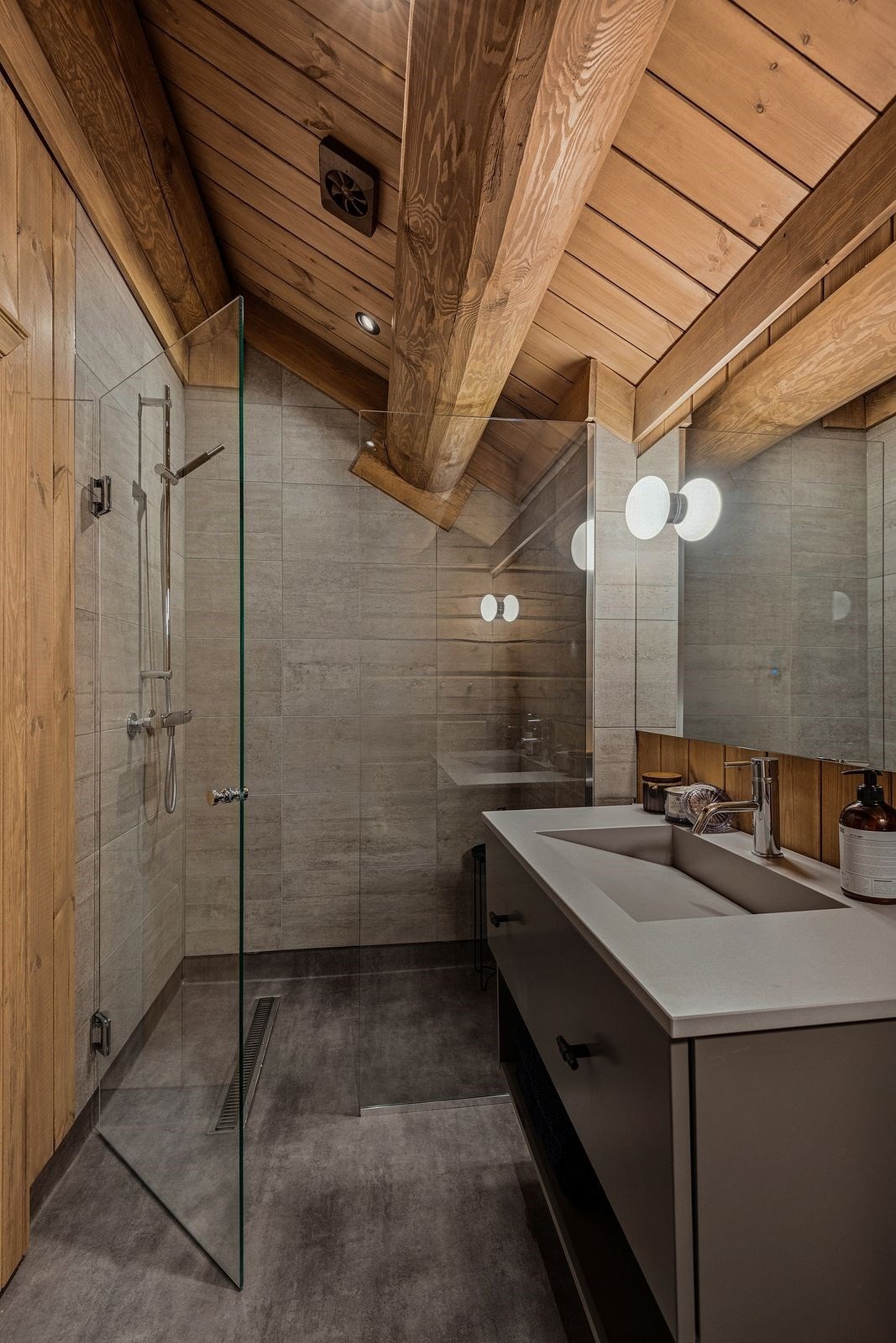 Dusjsonen har flislagte vegger og herdet glassdører, mens øvrige vegger er utført i laftet tømmer og panel som harmonerer med hyttas helhetlige stil. Galleribilde