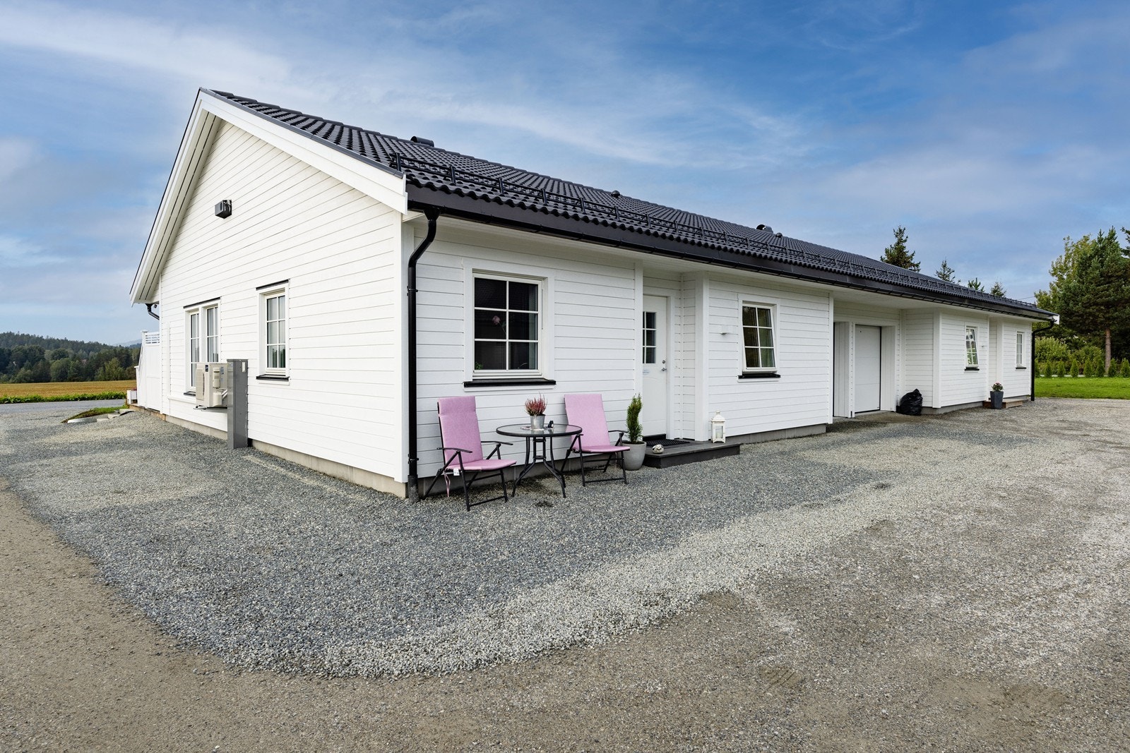 Tomten er opparbeidet med gruset innkjørsel, gressplen og beplantning. Galleribilde