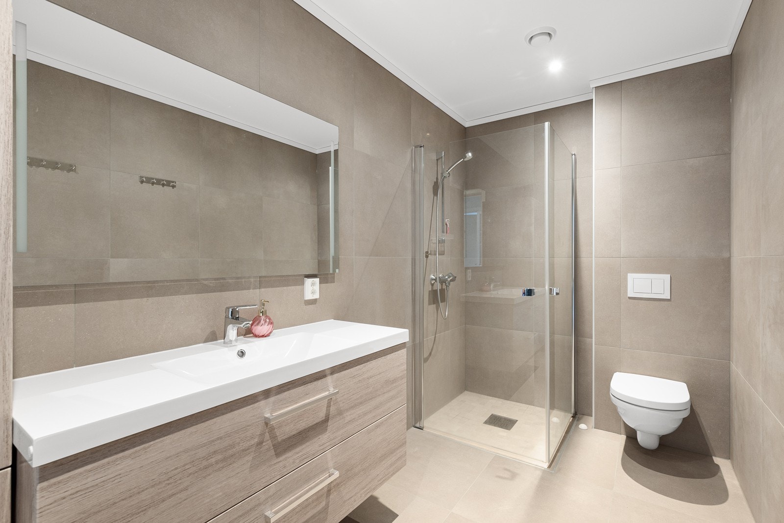 Stilrent og flislagt bad med elektriske varmekabler i gulv og malt himling med downlights. Galleribilde