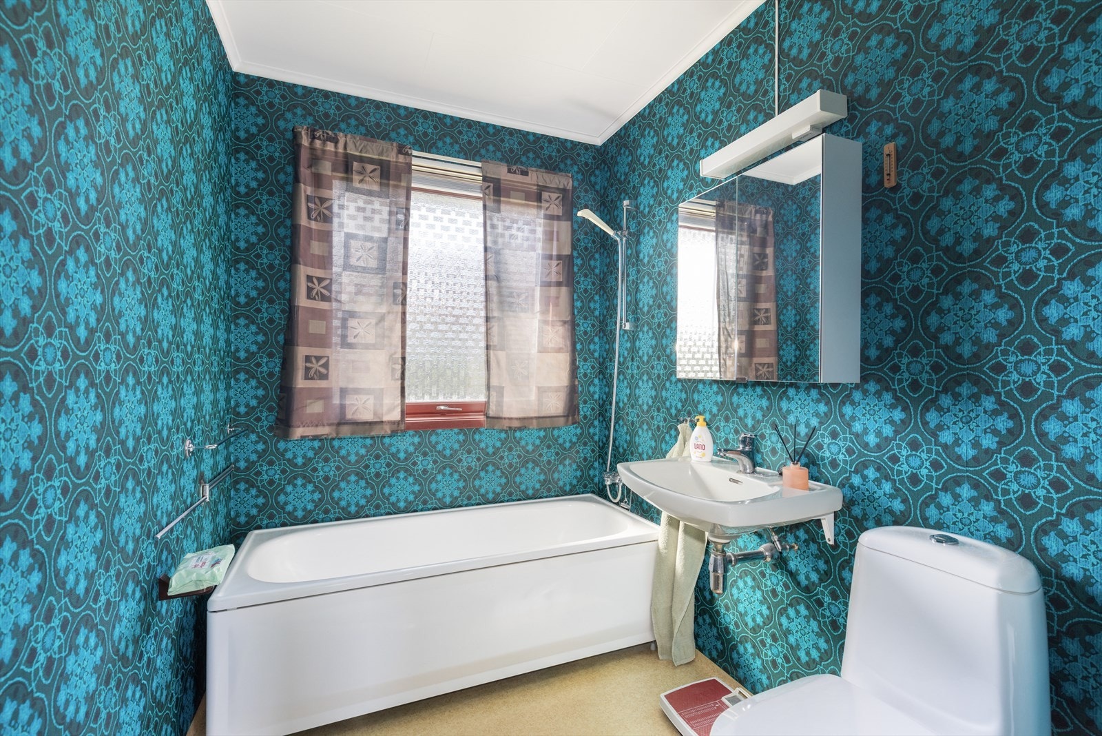 Badet er av eldre standard, utstyrt med badekar og vegghengt servant, samt praktisk speilskap og belysning. Byttet toalett i 2025. Galleribilde