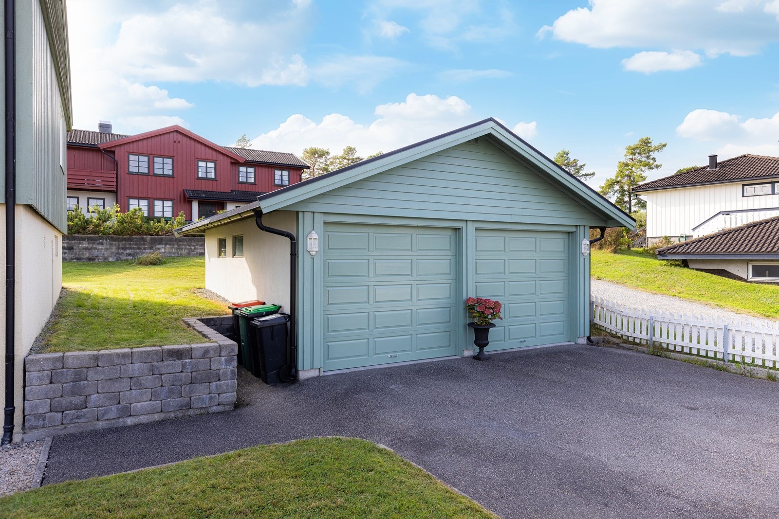 Frittstående dobbelgarasje oppført i 2001/02. Gruset gangsti fra asfaltert innkjørsel til boligens inngangsparti mot øst. Galleribilde