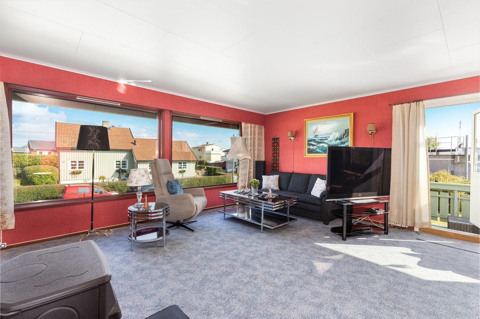 Romslig stue med store vindusflater som slipper inn godt med naturlig lys. Utvendig er det montert persienner for solskjerming. Galleribilde