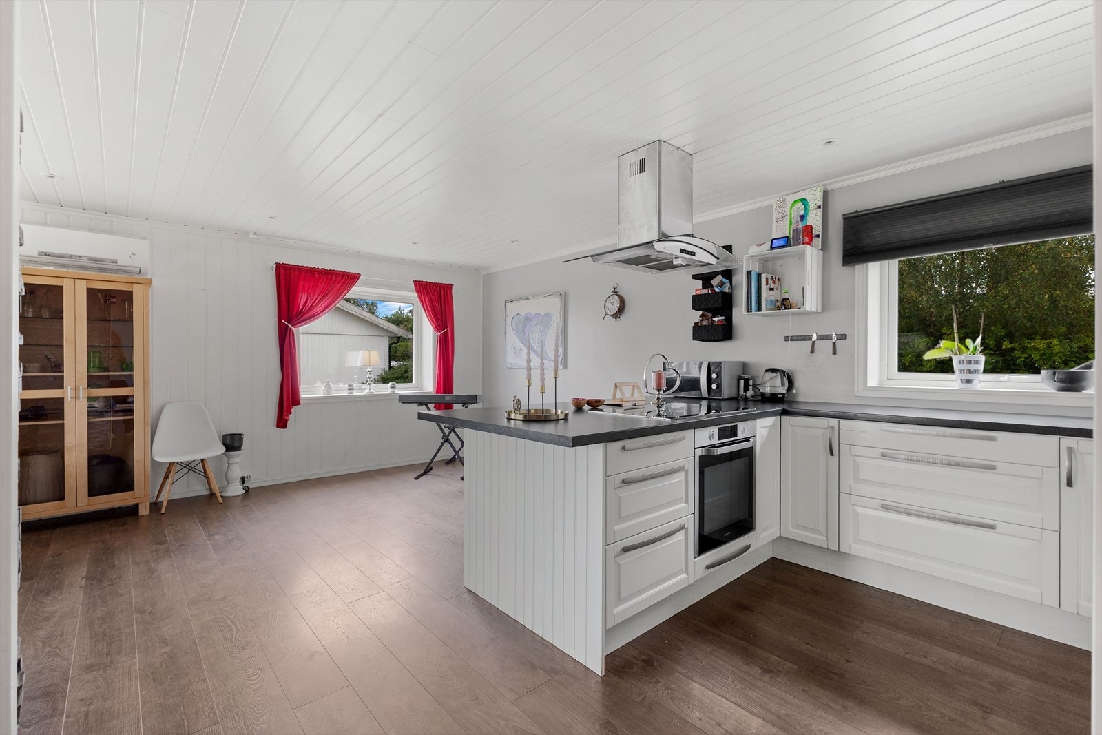 Innholdsrikt kjøkken med åpen løsning mot en romslig spisetstue og stue. Kjøkkenet har lyse profilerte fronter, laminert benkeplate og oppvaskkum. Galleribilde